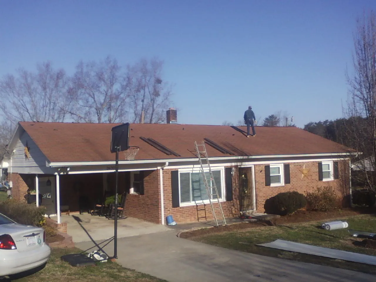 Roofer stripping a shingle roof on a brick ranch before metal panels in Mountain View