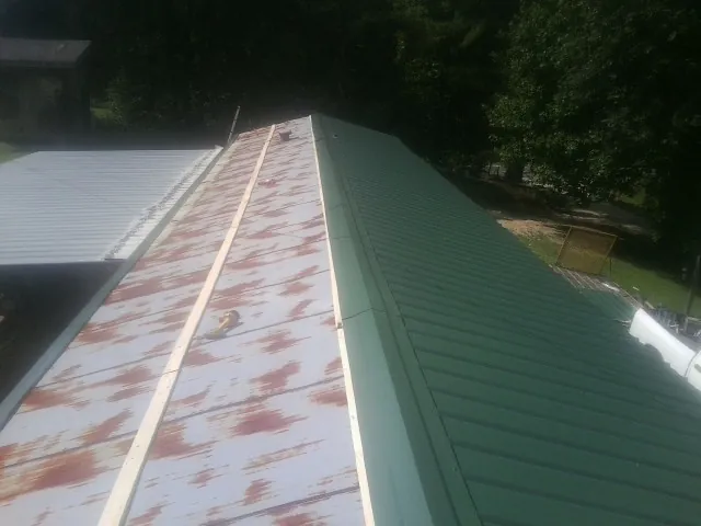 Old rusted panels beside newly installed green metal roofing — Wind Damage Roof Repair by Roofing Brothers in Mountain View