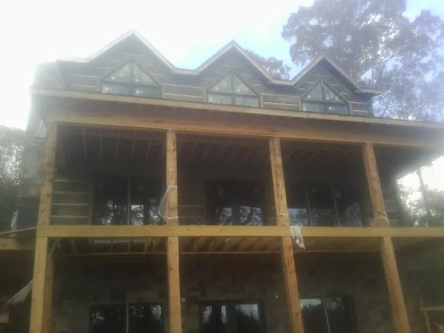 Dormers and porch framing on a large log home under construction — Roof Coating work by our crew in Mountain View