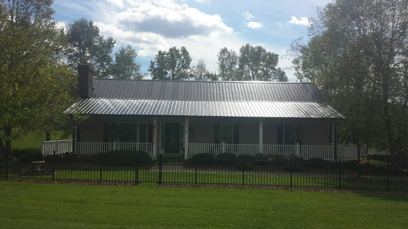 Gray metal roof on a brick ranch with a full width front porch — Gutter Guard Installation work by our crew in Mountain View